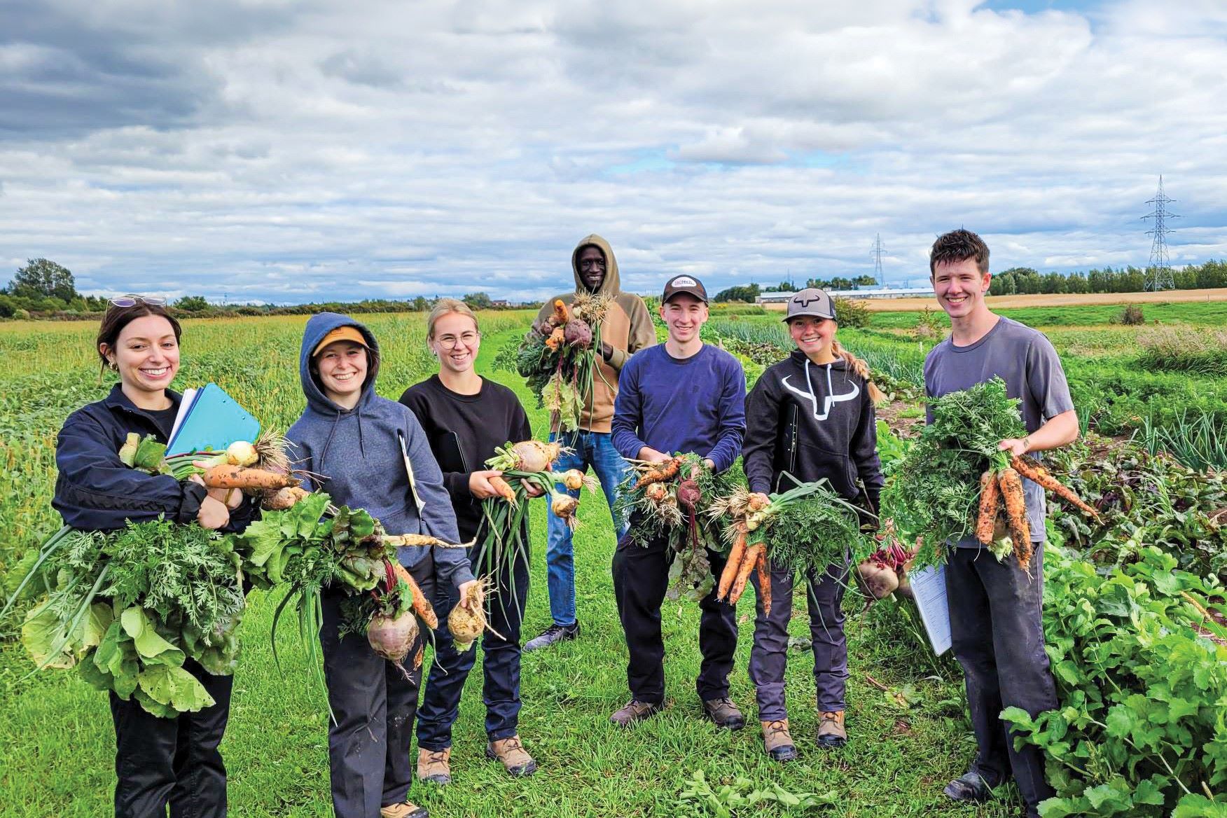 Étudiants du Cégep de Lévis arborant fièrement leur récolte de légumes dans les champs.